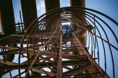 adam eski bir paslı dikey kablo merdiveni fabrika tırmanıyor