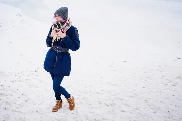 Chica de vapeo. retrato de invierno calle de una mujer hipster, pelo teñido de púrpura, un sombrero de punto gris y bufanda. mujer fuma un cigarrillo electrónico en la calle cerca del río cubierto de nieve —  Fotos de Stock