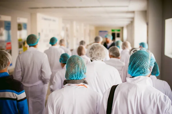 Grup endüstriyel üretimde insan. insanlar Beyaz önlük kamerada geri dön ve galoş fabrika turnede var