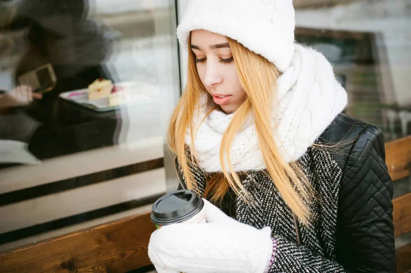 Woman in white scarf and hat drinks coffee — Stock Photo, Image