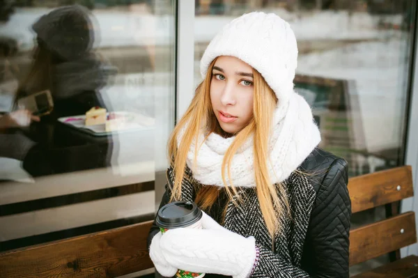 Woman in white scarf and hat drinks coffee — Stock Photo, Image