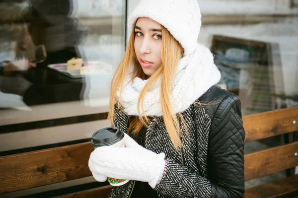 Woman in white scarf and hat drinks coffee — Stock Photo, Image