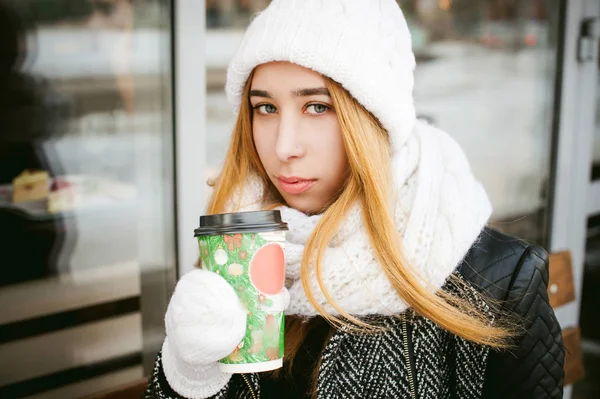 Woman in white scarf and hat drinks coffee — Stock Photo, Image