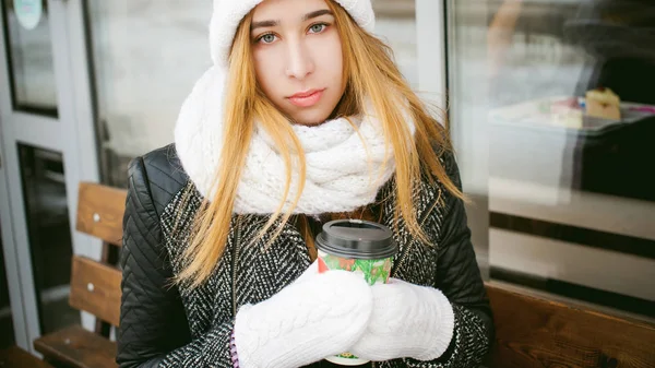 Woman in white scarf and hat drinks coffee — Stock Photo, Image