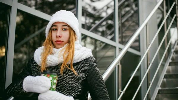 Vrouw in witte sjaal en muts drinkt koffie — Stockfoto