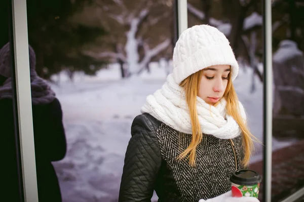 Femme en écharpe blanche et chapeau boit du café — Photo