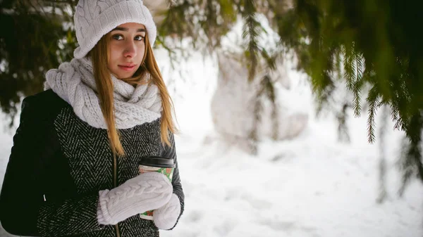 Retrato de mulher bonito em cachecol branco e chapéu casaco de malha ao ar livre fundo de neve e ramos de abeto borrados no inverno — Fotografia de Stock