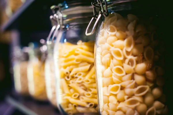 pasta in the jar. on kitchen shelves are different kinds of pasta in glass jars