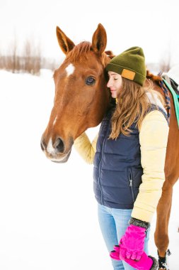 Kadın binici ve at açık havada. Onu aygır, kışın açık havada olan güzel bir kadın portresi. sarılma ve hayvan sevecen kız