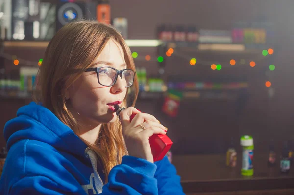 Hermosa mujer joven con gafas de fumar cigarrillo electrónico — Foto de Stock