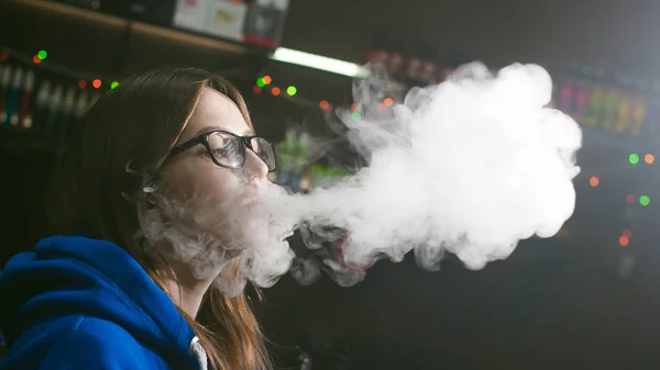 Hermosa mujer joven con gafas de fumar cigarrillo electrónico —  Fotos de Stock