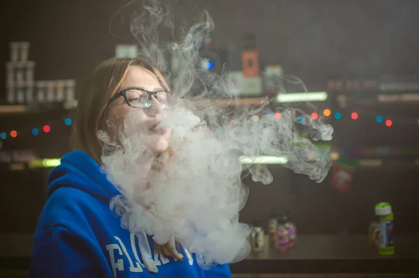 Beautiful young woman with glasses smoking electronic cigarette — Stock Photo, Image