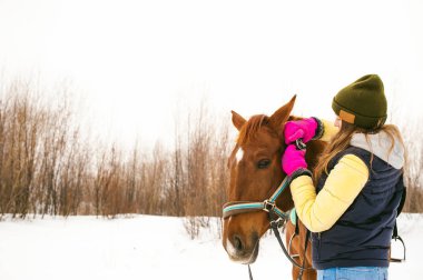 Kış giysileri ve birlikte beyaz kar karşı durmak için at kadın. sevgi ve atlar için bakım. 
