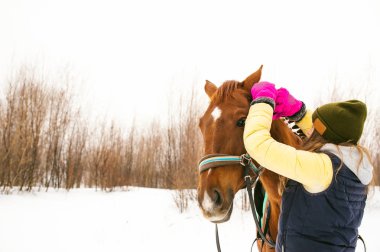 Kış giysileri ve birlikte beyaz kar karşı durmak için at kadın. sevgi ve atlar için bakım. 