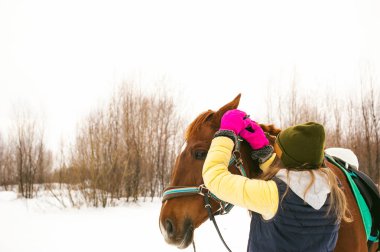 Kış giysileri ve birlikte beyaz kar karşı durmak için at kadın. sevgi ve atlar için bakım. 