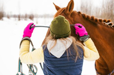 Kış giysileri ve birlikte beyaz kar karşı durmak için at kadın. sevgi ve atlar için bakım. 