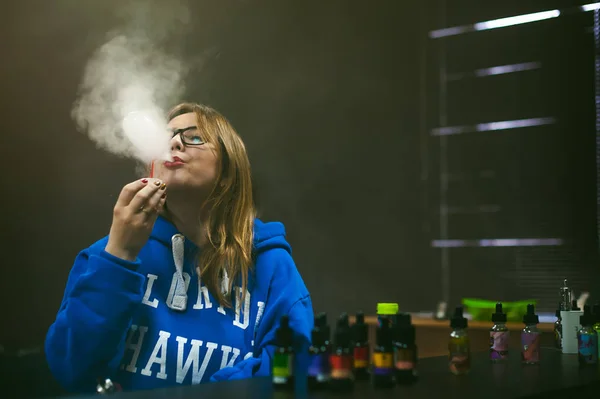 Leuke jonge vrouw, de verkoper in vape shop winkel, elektronische sigaret roken — Stockfoto