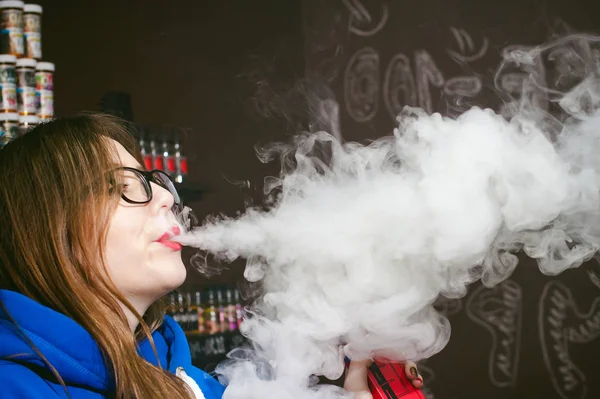 Joven linda mujer, el vendedor en la tienda de vape, fumar cigarrillo electrónico — Foto de Stock