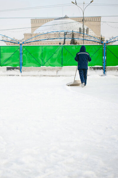 janitor cleans snow shovel on the ice rink