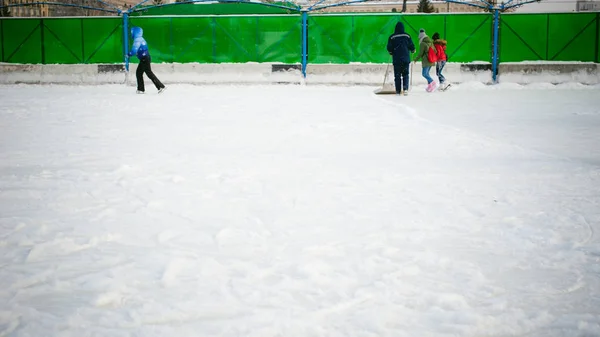 Conserje limpia la pala de nieve en la pista de hielo — Foto de Stock