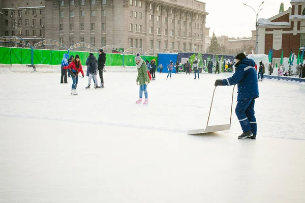 Conserje limpia la pala de nieve en la pista de hielo — Foto de Stock