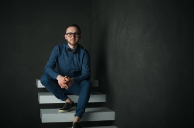 karanlık duvar arka plan mavi tişört ve kot üzerinde genç hippi erkek portresi stüdyo. 