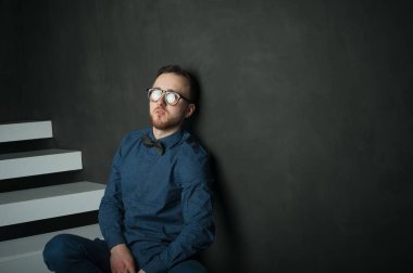 karanlık duvar arka plan mavi tişört ve kot üzerinde genç hippi erkek portresi stüdyo. 