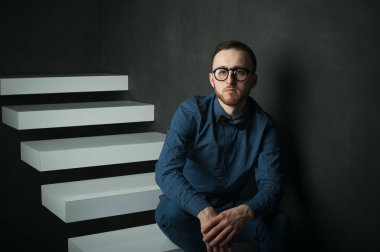 karanlık duvar arka plan mavi tişört ve kot üzerinde genç hippi erkek portresi stüdyo. 