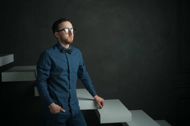 karanlık duvar arka plan mavi tişört ve kot üzerinde genç hippi erkek portresi stüdyo. 