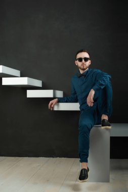 karanlık duvar arka plan mavi tişört ve kot üzerinde genç hippi erkek portresi stüdyo. 