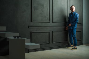 karanlık duvar arka plan mavi tişört ve kot üzerinde genç hippi erkek portresi stüdyo. 