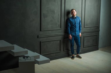 karanlık duvar arka plan mavi tişört ve kot üzerinde genç hippi erkek portresi stüdyo. 