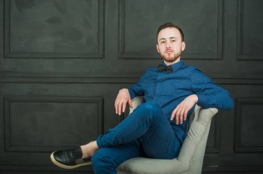 karanlık duvar arka plan mavi tişört ve kot üzerinde genç hippi erkek portresi stüdyo. 