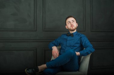 karanlık duvar arka plan mavi tişört ve kot üzerinde genç hippi erkek portresi stüdyo. 