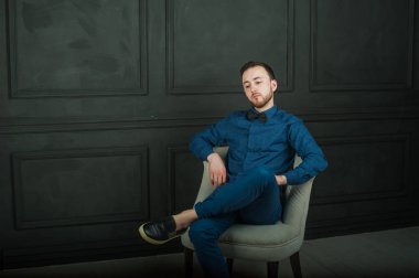 karanlık duvar arka plan mavi tişört ve kot üzerinde genç hippi erkek portresi stüdyo. 