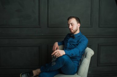 karanlık duvar arka plan mavi tişört ve kot üzerinde genç hippi erkek portresi stüdyo. 