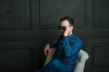 karanlık duvar arka plan mavi tişört ve kot üzerinde genç hippi erkek portresi stüdyo. 