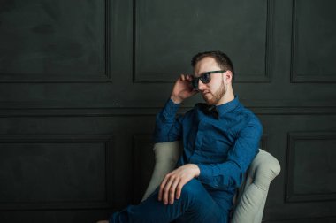 karanlık duvar arka plan mavi tişört ve kot üzerinde genç hippi erkek portresi stüdyo. 