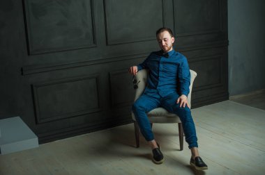 karanlık duvar arka plan mavi tişört ve kot üzerinde genç hippi erkek portresi stüdyo. 