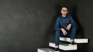 karanlık duvar arka plan mavi tişört ve kot üzerinde genç hippi erkek portresi stüdyo. 