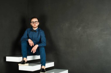 karanlık duvar arka plan mavi tişört ve kot üzerinde genç hippi erkek portresi stüdyo. 