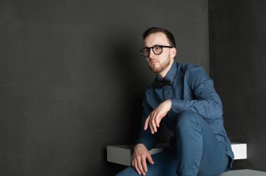 karanlık duvar arka plan mavi tişört ve kot üzerinde genç hippi erkek portresi stüdyo. 