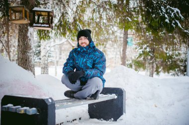 Erkekler bir kış Parkta yürümek. adam iyi mizah ve gülümseme, açık havada, yürüyüş giyim sıcak ile dinlenmek için bir bankta oturdu