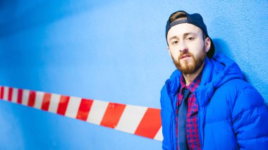 mavi duvar rengi park yerinde yakınındaki genç bir adam portresi. Bir park üzerinde poz sıcak ceket sakallı bir adam