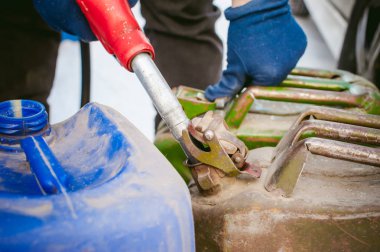 yetişkin adam kışın benzin yakıt istasyonu ile bir araba doldurur. teneke kutu ve yakıt tankı sıvı dökme, elinde tutan meme adam yakıt ikmali