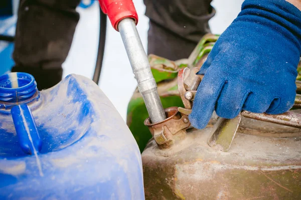 yetişkin adam kışın benzin yakıt istasyonu ile bir araba doldurur. teneke kutu ve yakıt tankı sıvı dökme, elinde tutan meme adam yakıt ikmali