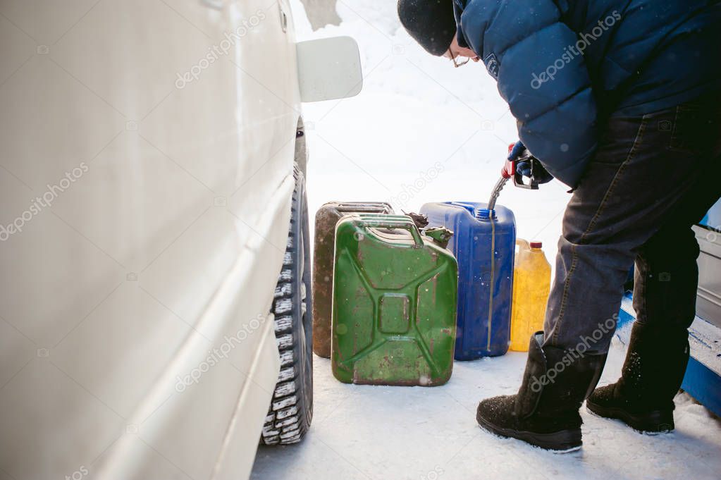 adult man fills a car with petrol at a fuel station in the winter