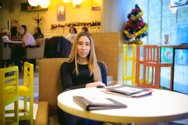 bir fincan elinde tutan bir siyah elbiseli genç kadın