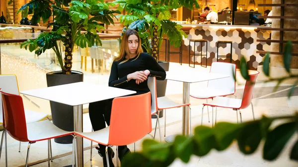 Jonge vrouw in een zwarte jurk shopping mall — Stockfoto