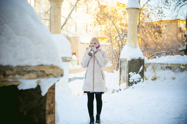 Jovem mulher vestida com roupas quentes bebendo café takeaway da xícara na rua no inverno — Fotografia de Stock